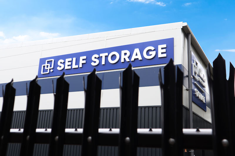 Self storage in St Neots. Image shows the exterior view of a Cinch self storage facility with a dark fence in the foreground.