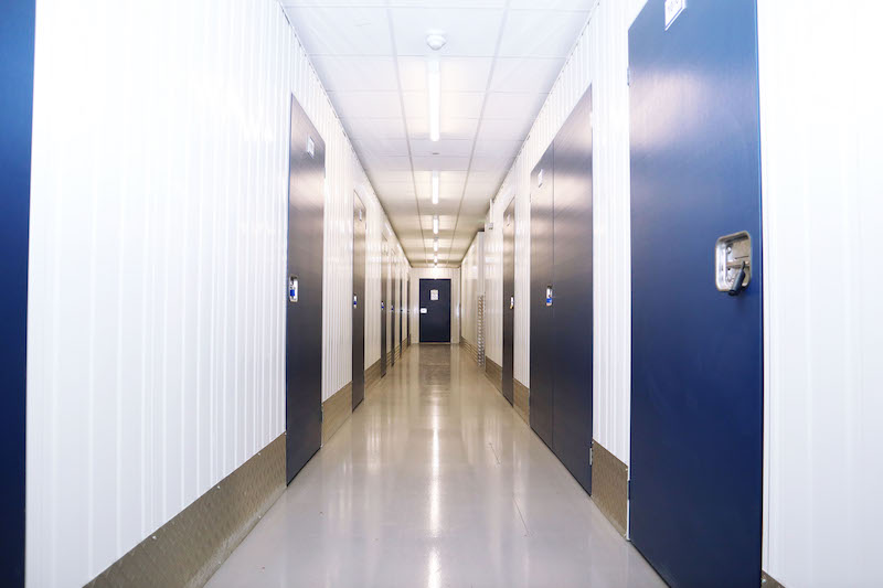 Storage unit in Godmanchester. Image shows the interior corridor of a storage unit facility with blue storage unit doors on either side.