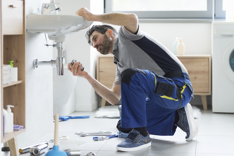 Storage units Watford. Image shows plumber under sink.