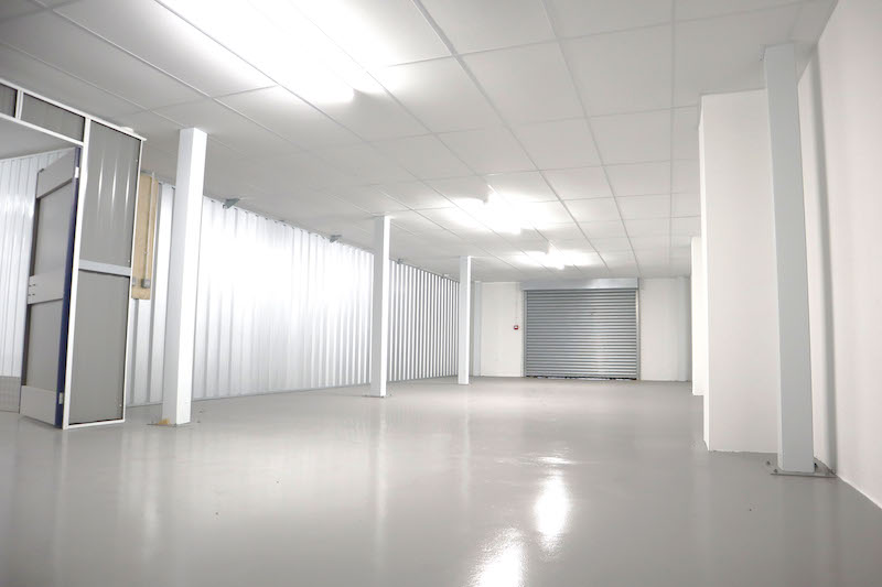 Storage in Bedford. Image shows a large empty storage unit with white walls and ceiling and grey polished concrete floor.