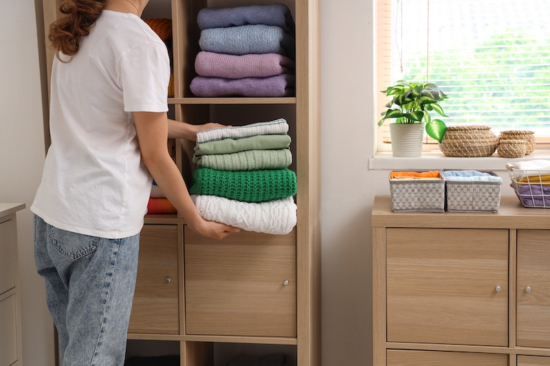 Storage Kempston. Image shows woman folding jumpers and organising her wardrobe.