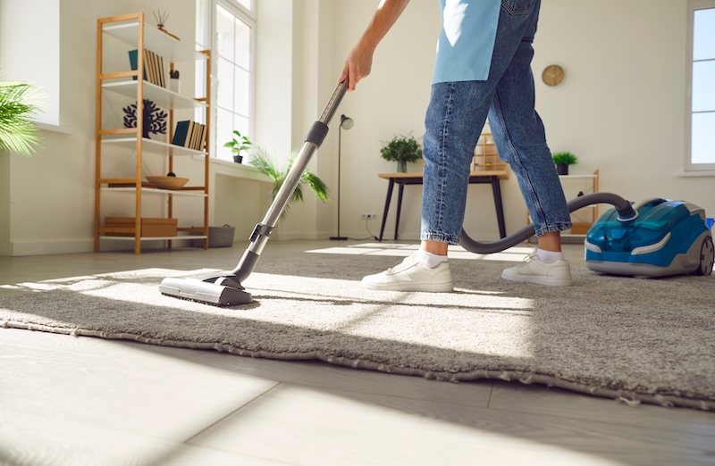 Storage Bedford. Image shows person in blue jeans hoovering a grey rug.