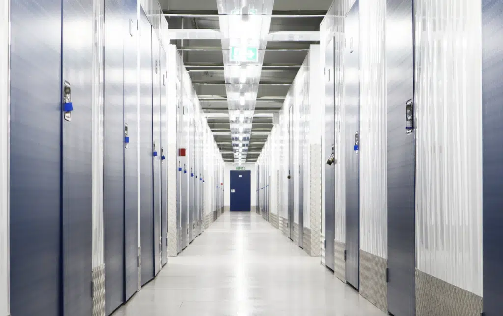 Storage units in Bedford. Image shows interior of storage facility with a corridor of storage units with blue doors on either side.