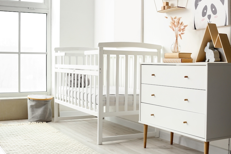 Self storage in Southend. Image shows the interior of a nursery with a cot and chest of drawers in a light cream colour.