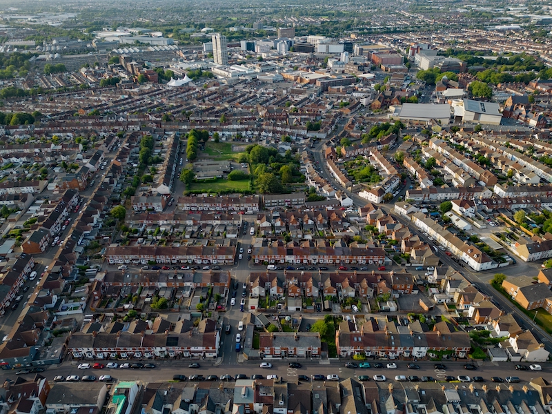 5 things to do in Swindon. Image shows Swindon town centre at sunset. Aerial view of the streets with houses and cars towards train station and retail park.