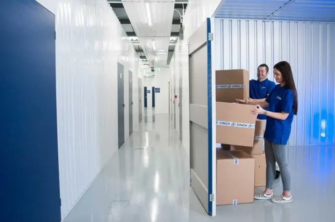 Two employees stacking cardboard boxes in a storage unit