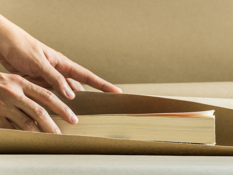 How to store books. Image shows someone wrapping a book ready for storage.