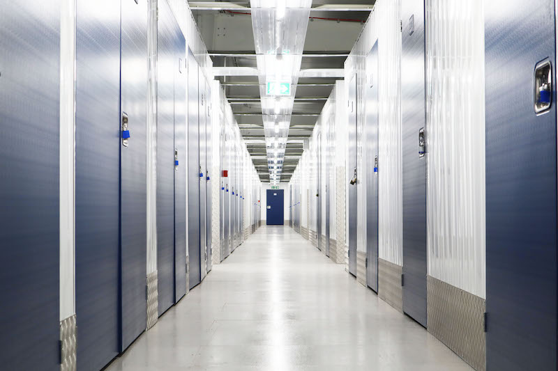 Storage unit to rent Swindon. Image shows a corridor of storage units with blue doors. 