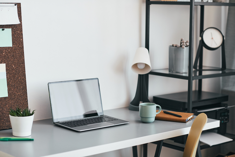 Offices in Letchworth. Image shows a small office with a white desk, silver laptop, lamp and grey mug on it.