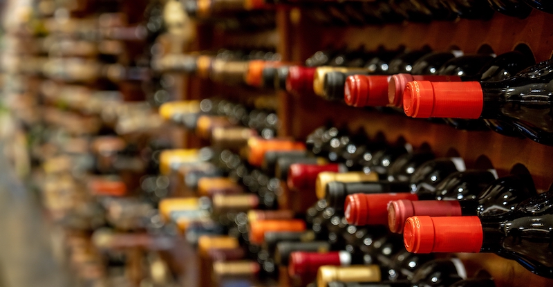 How to store wine. Image shows wine bottles lined up and stacked on shelves