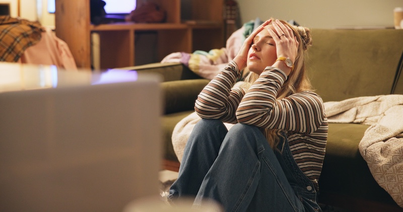 House move storage Wisbech. Image shows a woman sitting on the floor with her head in her hands surrounded by moving boxes.