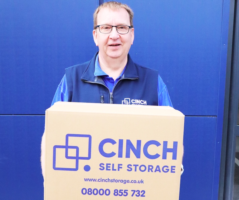 Self storage in Cambridgeshire. Image shows a cinch self storage employee holding a Cinch Storage branded cardboard box.