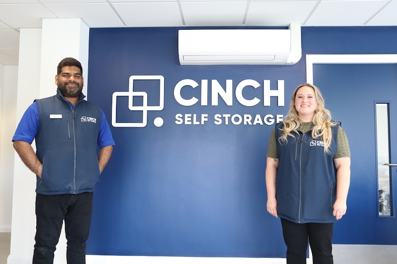 Storage unit to rent Wisbech. Image shows two Cinch Self Storage employees standing infront of the Cinch Self Storage logo sign.