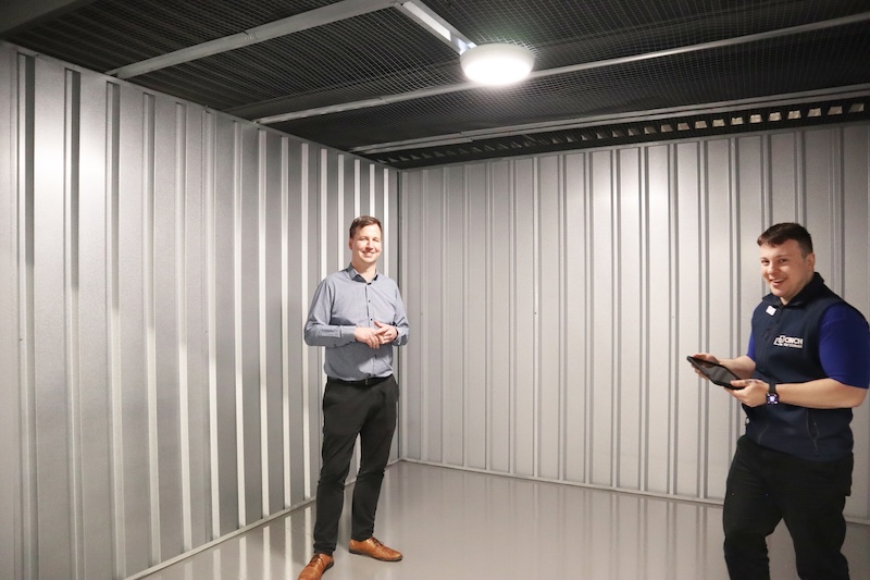 Do self storage units come with electricity. Image shows two men standing inside a storage unit with a lightbulb lit above them.
