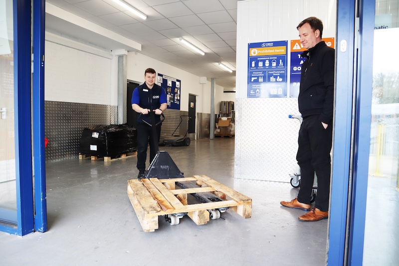 Essex self storage. Image shows a couple of men inside a self storage facility, wheeling a palette inside.
