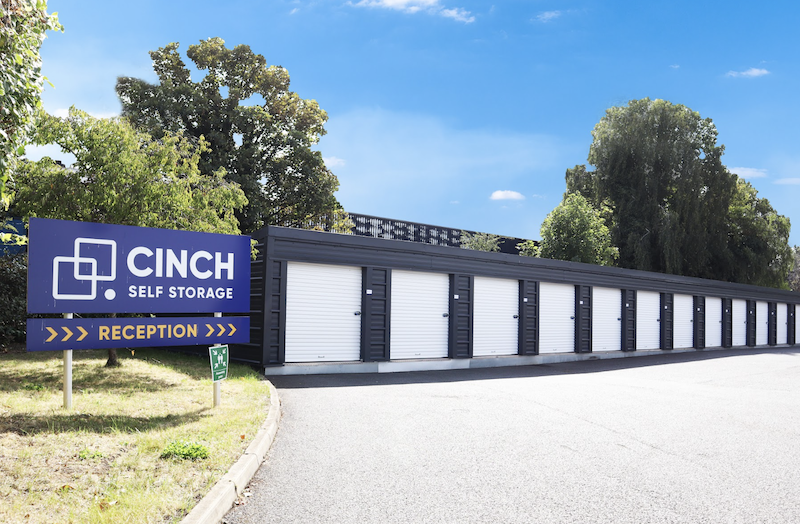 External lockups. Image shows a series of drive up storage units, with a blue Cinch Self Storage sign.