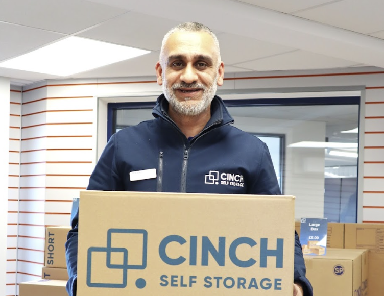 Flexible self storage. Image shows a man holding a cinch self storage cardboard box smiling to camera.