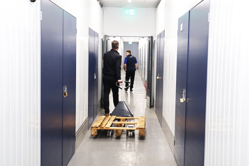 Huntingdon long term storage. Image shows two men walking down the corridor of a storage facility wheeling a palette.