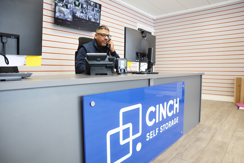 Kent business storage. Image shows a Cinch storage employee sitting at the front desk taking a phone call.
