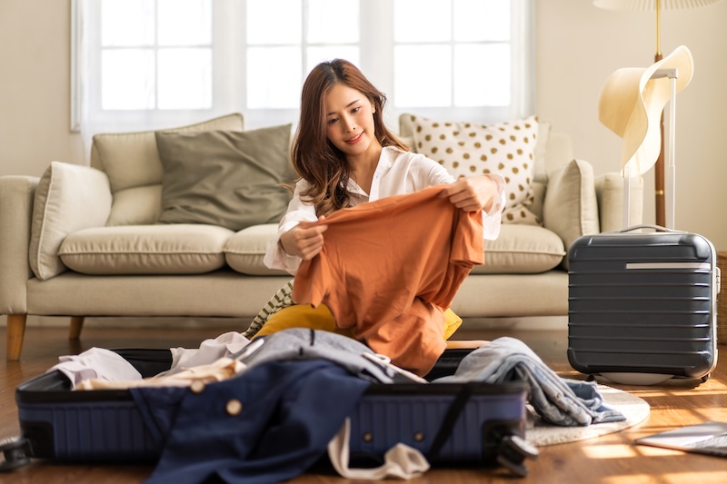 Summer storage. Image shows a woman sorting through suitcases filled with clothes.