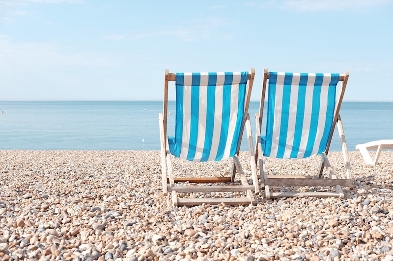 7 things to do when you retire in Brighton. Image shows two Timber beach chairs on Brighton Beach, England.