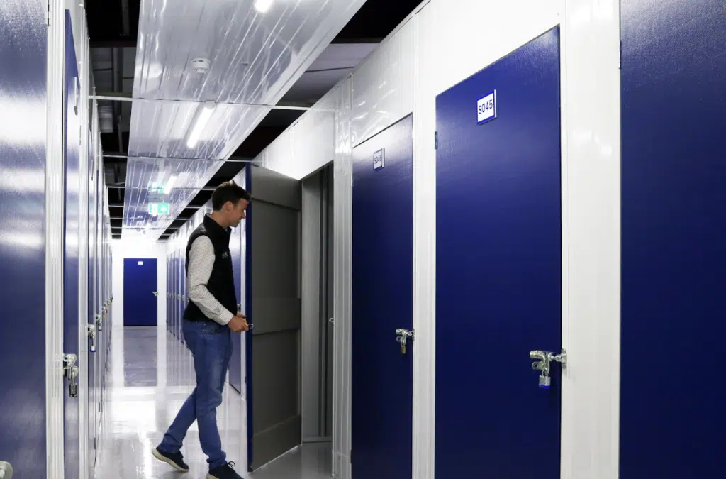 Best storage in Leighton Buzzard. Image shows a man opening a door into a storage unit in the storage unit corridor.