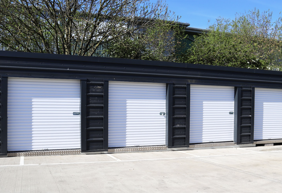 Drive up storage. Image shows a row of drive up storage units with white doors.