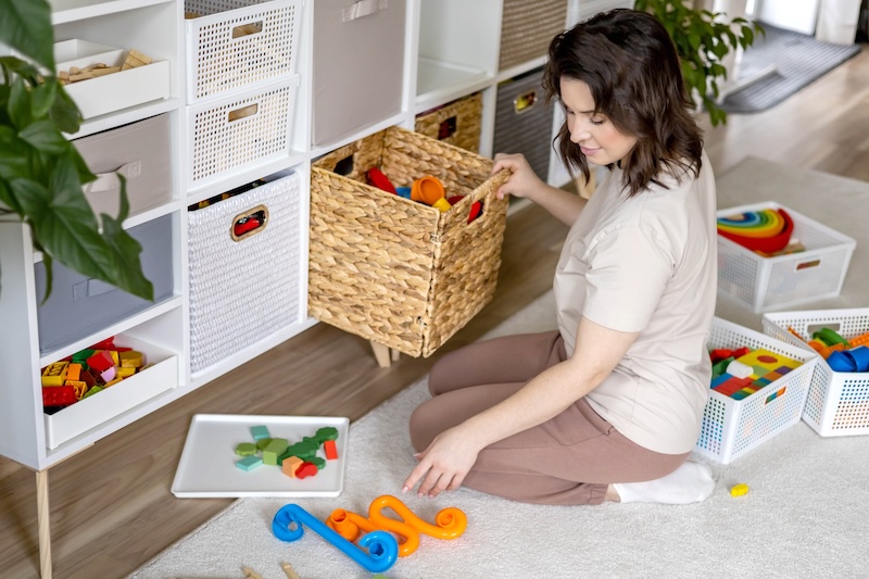 Toy storage ideas. Image shows a woman organising toys into a drawer.