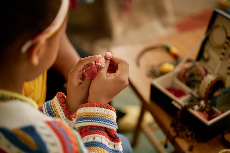 Long term storage Southend. Close up of child's hands holding colourful earrings organising accessories in jewellery box