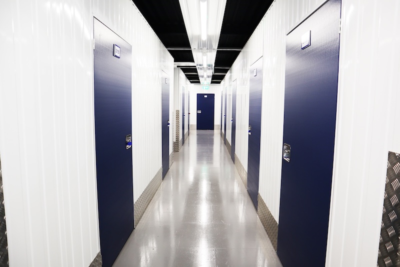 Short term storage Brighton. Image shows a corridor with blue doors leading to storage units on either side.