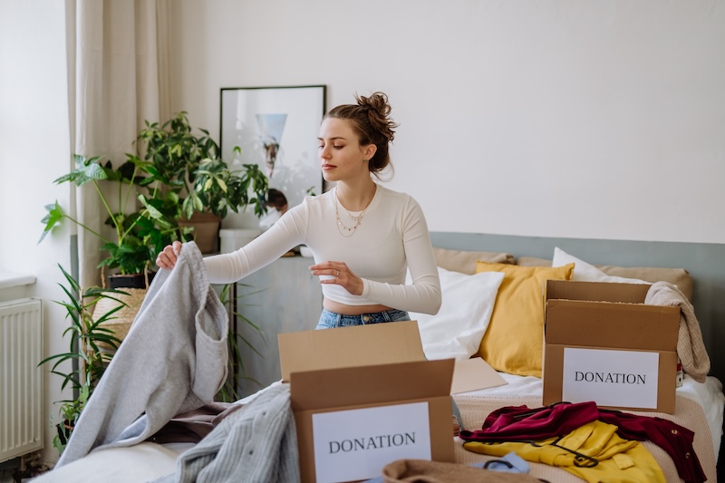 Short term storage Seaford. Image shows a young woman organising her clothes into donation boxes and decluttering.