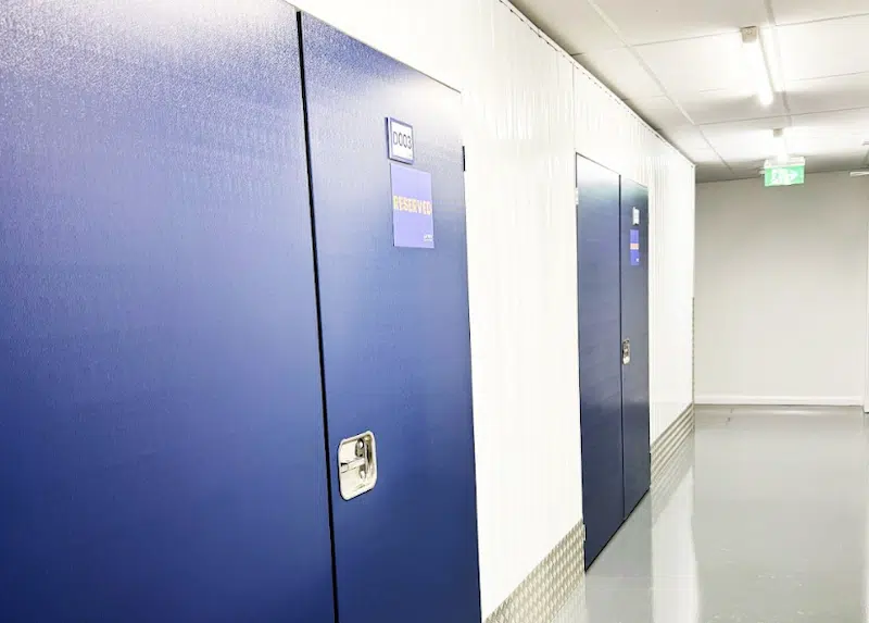 Low cost storage Bedford. Image shows a storage unit corridor with blue doors and a reserved sign on one of the doors with orange text.