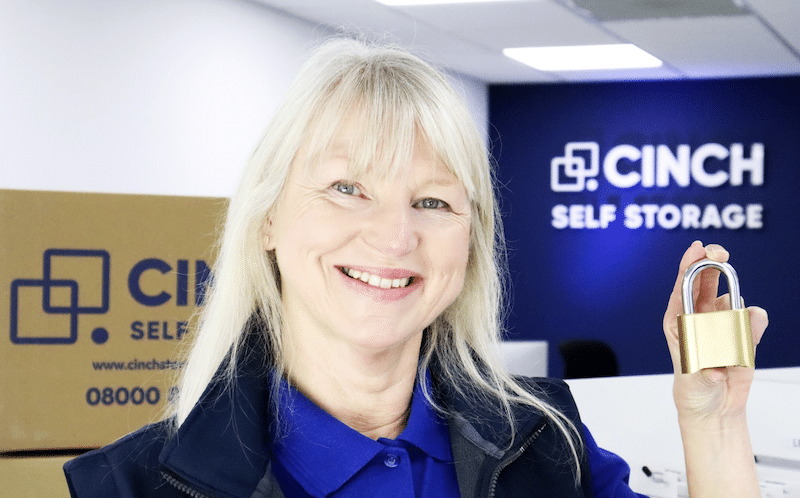 Low cost storage Brighton. Image shows a Cinch Storage Employee smiling at the camera and holding a gold padlock.