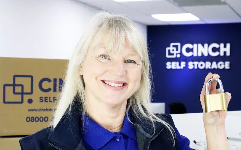 Low cost storage Brighton. Image shows a Cinch Storage Employee smiling at the camera and holding a gold padlock.
