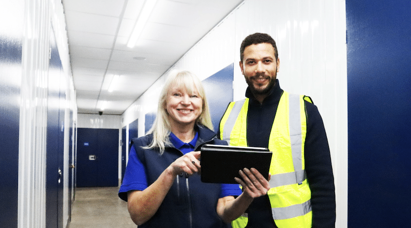 Storage in Newcastle. Image shows a Cinch Self Storage employee showing a builder in high vis a quote on the ipad inside the storage rooms corridor.