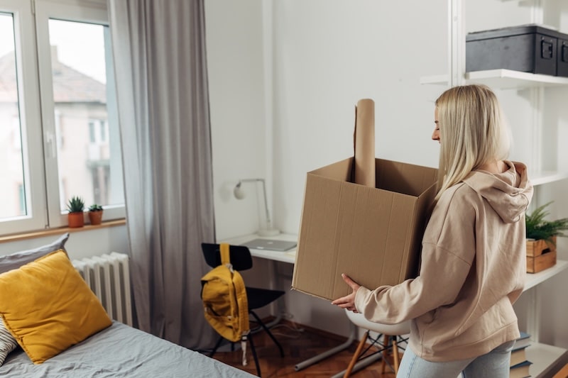 Storage Shoreham-by-sea. Image shows a student packing up her bedroom carrying a cardboard box.