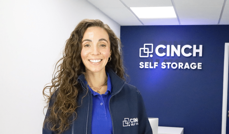 Best storage in Enfield. Image shows a Cinch Self Storage employee in front of the logo in reception.
