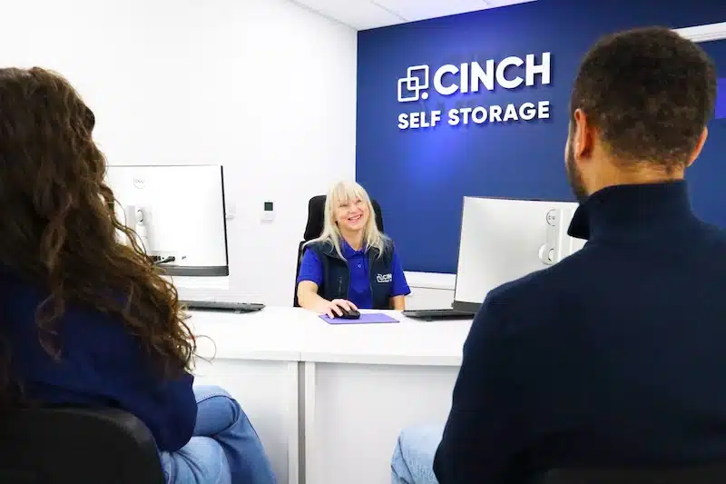 Newcastle ultimate guide to self storage. Image shows a Cinch Storage employee sitting at the desk smiling at customers. 
