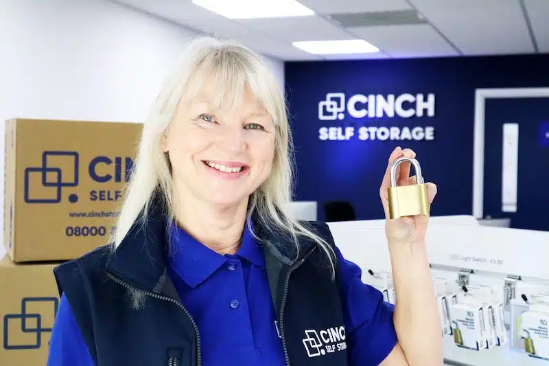 Secure storage Newcastle. Image shows a Cinch Storage employee holding a padlock infront of the logo.