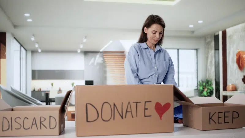 Self storage Exeter. Image shows a woman decluttering her home by putting clothes into donate, keep and discard boxes.