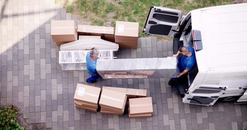 Storage facilities in Exeter. Image shows removal men carrying a bookcase into a removals van, surrounded by cardboard boxes.