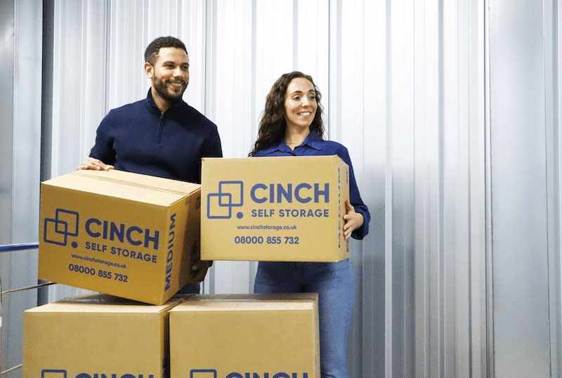 Storage units Exeter. Image shows a young couple delivering their Cinch Self Storage cardboard boxes into their storage unit.