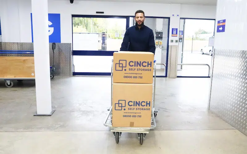 Long term storage Exeter. Image shows a man walking with a trolley full of Cinch Self Storage Boxes. 