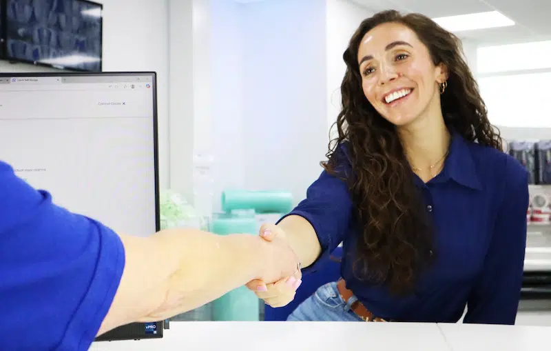 Low cost storage Exeter. Image shows a woman shaking hands with a Cinch Storage employee securing her self storage. 