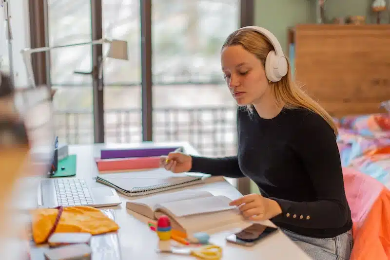 Storage rooms in Exeter. Image shows a young female student studying at her desk with headphones on. 