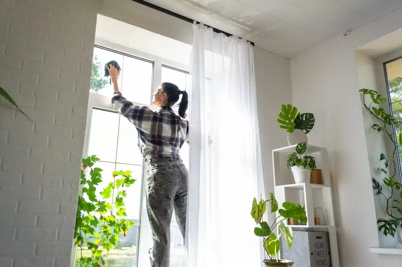 Storage rooms in Watford. Image shows a woman manually washing the windows with a rag and spray cleaner. 