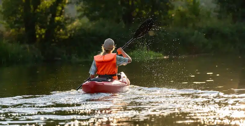 Storage unit Exeter. Image shows a woman in an orange life vest paddling down the river in a red kayak. 