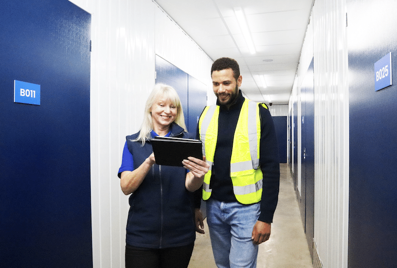 Business storage Paulton. Image shows a builder being shown a quote on an ipad at Cinch Self Storage in the corridor of storage units. 