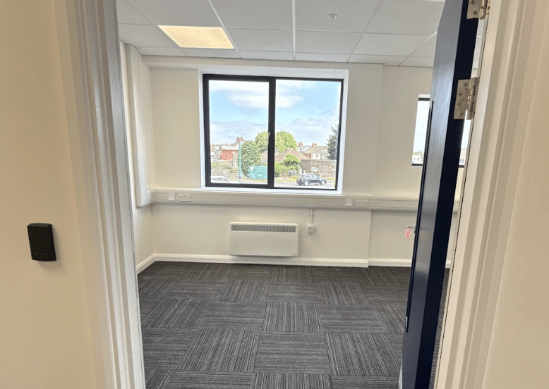 Leighton Buzzard office space. Image shows an empty office with large window and carpeted floor at Cinch Self Storage.