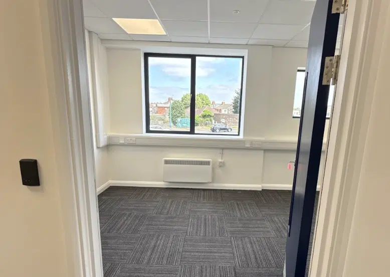 Leighton Buzzard office space. Image shows an empty office with large window and carpeted floor at Cinch Self Storage.